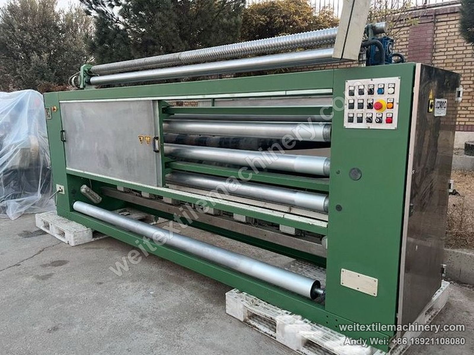 Used Corino photoelectric weft straightener, full view with green frame, stainless guide rolls, push-button panel and CORINO plate