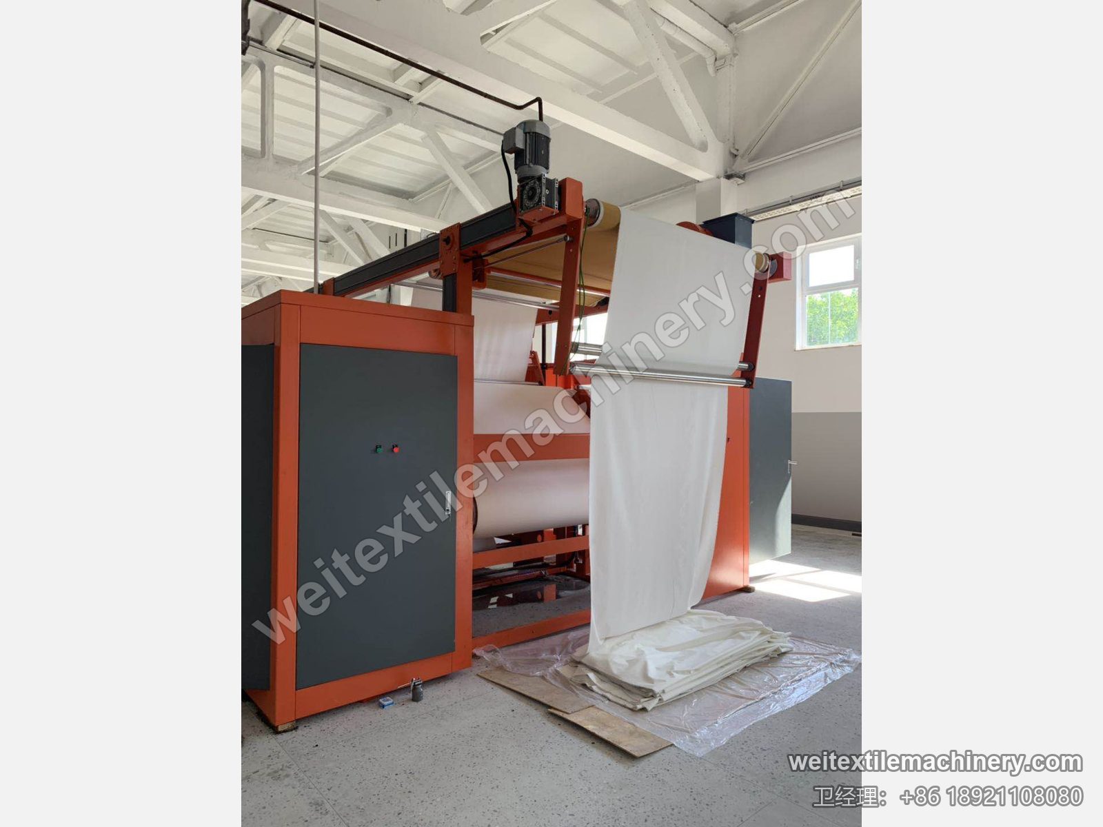 二手 M-Tec Contipress 400 硅胶导带压光机进布端，织物导入、顶部电机与橙色机架