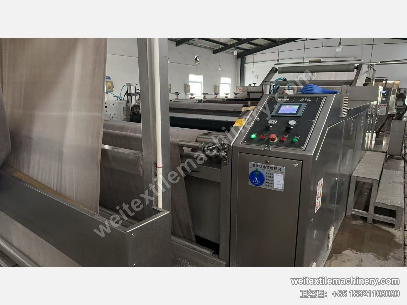 二手 TMT STC 同系列湿刷毛定型机（面板标 6D+6R）运行中，织物进机、触摸屏面板与设备状态标识牌
