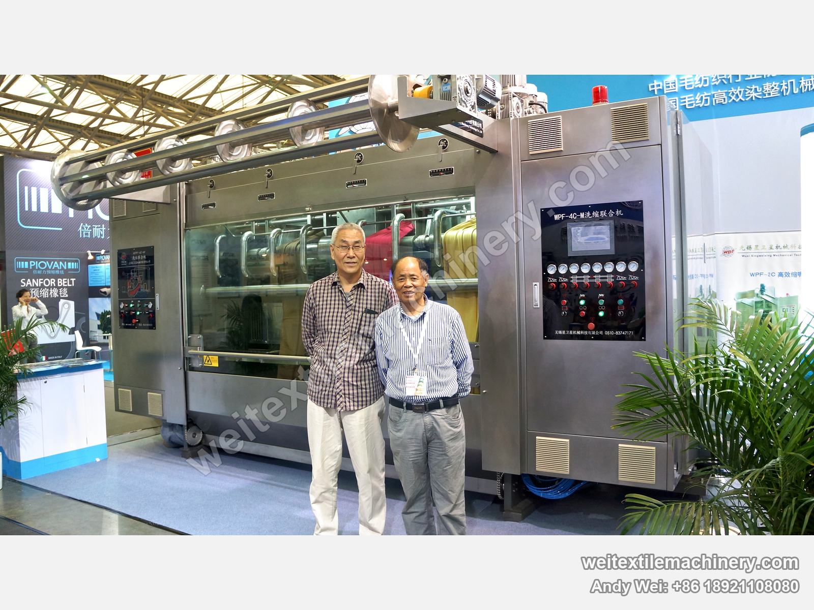 Two guests in front of the WPF-4C-M scouring and milling machine on the 2013 stand, coloured fabric behind the window