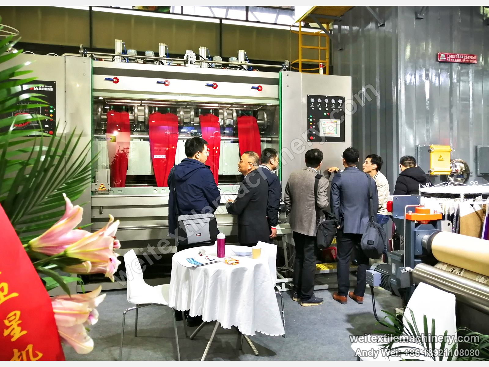 Visitors gathered at a four-channel scouring and milling machine on the 2019 stand, red fabric in each channel
