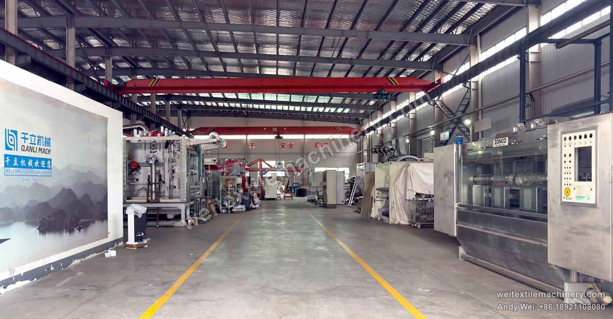 Main aisle of the QL workshop, a mural reading Welcome to Qianli Machinery, Since 1991 on the left and machines on the right